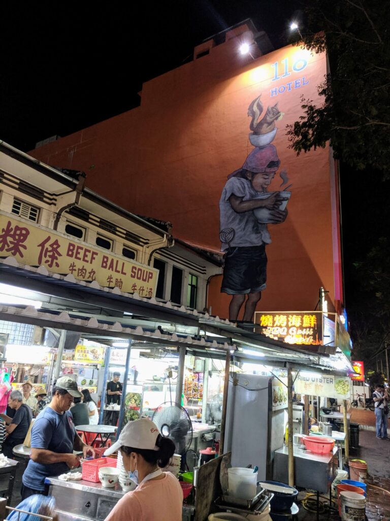 Night food markets with towering mural on the wall behind