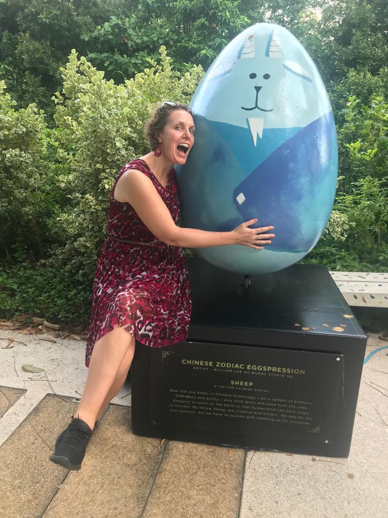 A woman hugging a giant painted egg