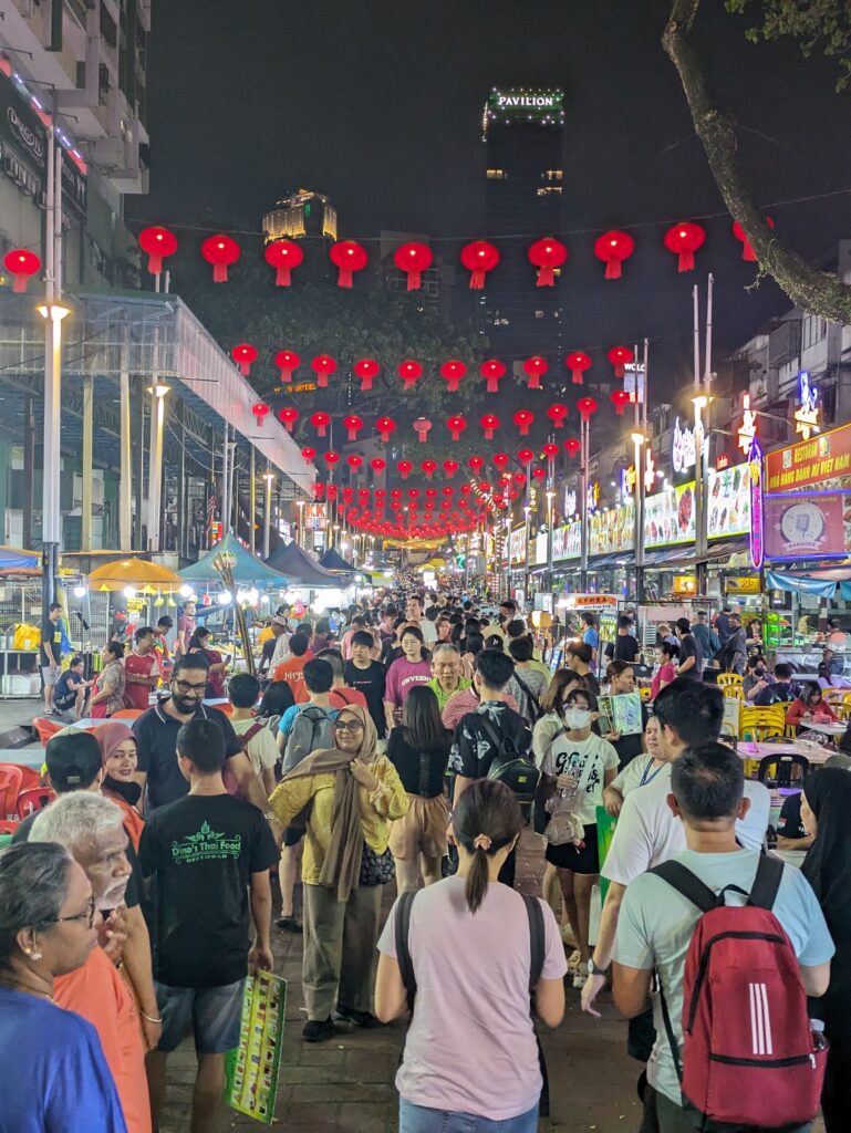 a crowded street at a night market with red lanterns hanging above