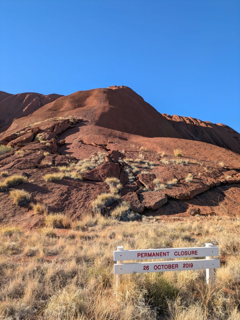 A sign in front of a large rock formation, indicating that the rock should not be climbed