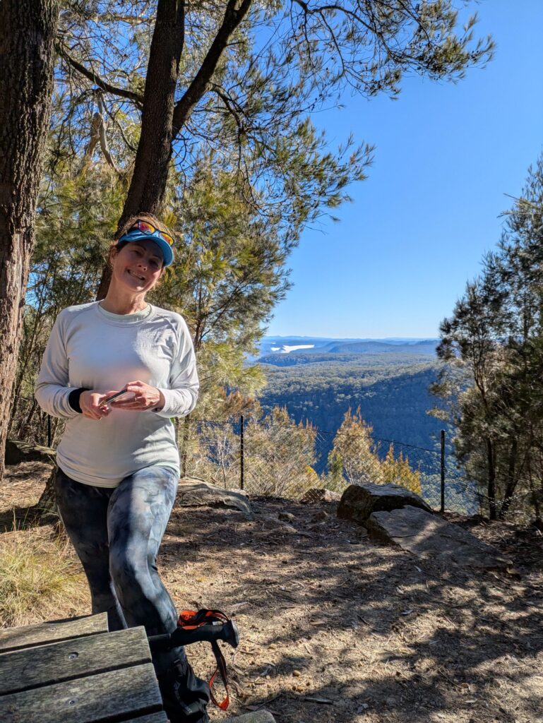 A woman at a lookout with a view behind her over the mountains into the distance