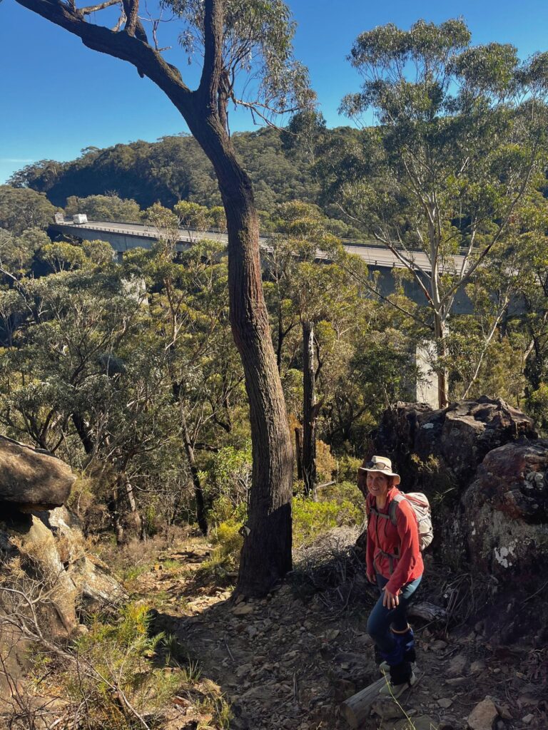 A woman bushwalking with a large motorway in the background