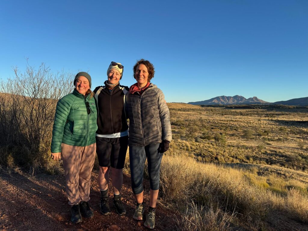 3 friends posing outside with a mountain in the distance