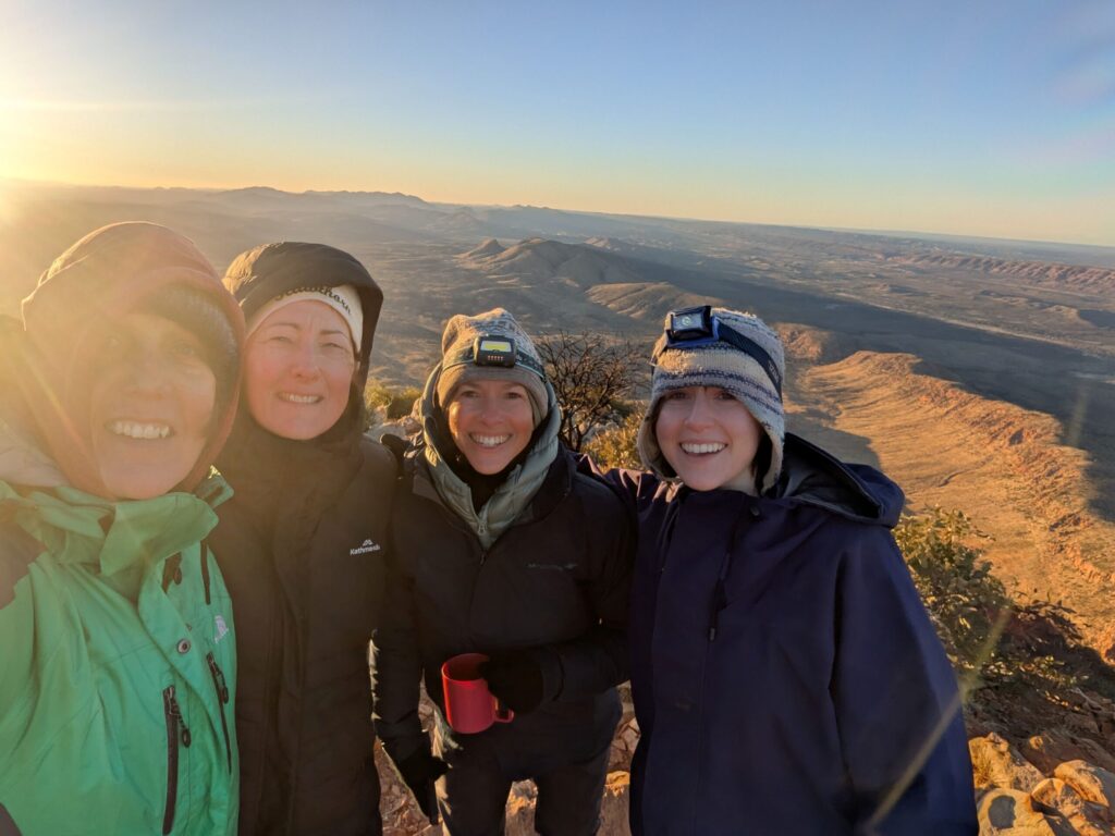Four women, rugged up cause the weather is cold, at the top of a mountain