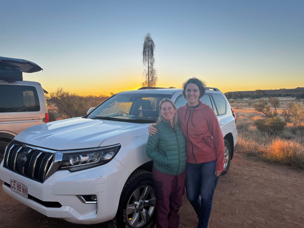 Two friends standing beside their 4WD car