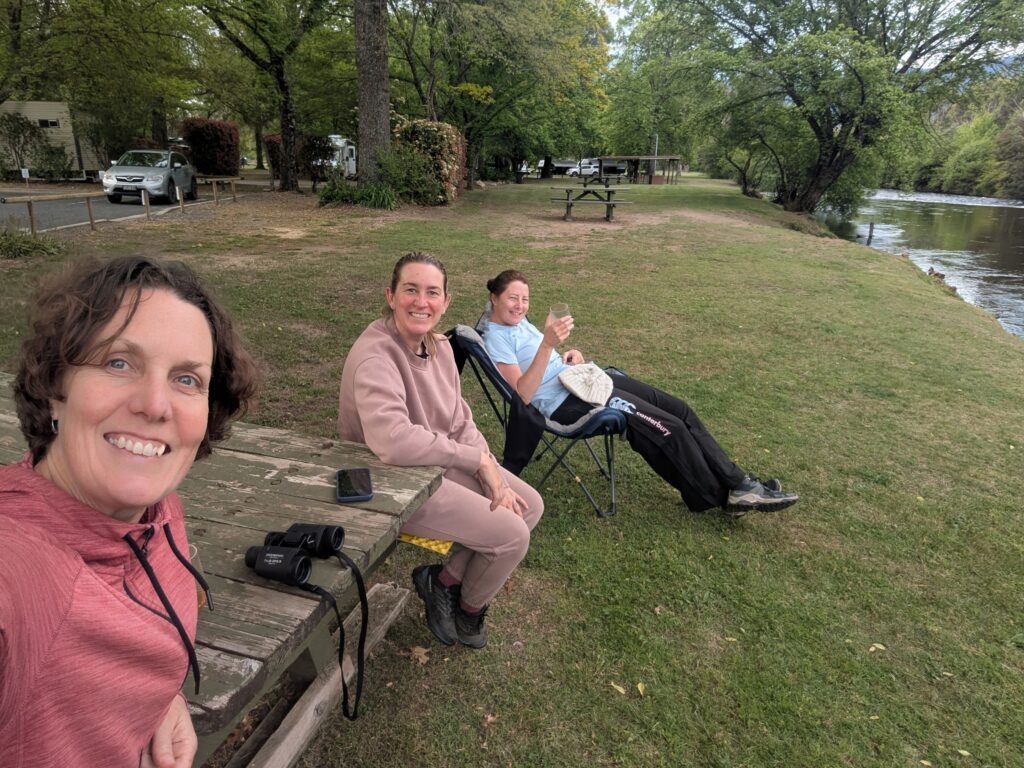 #3 friends sitting by a river enjoying a sunset drink