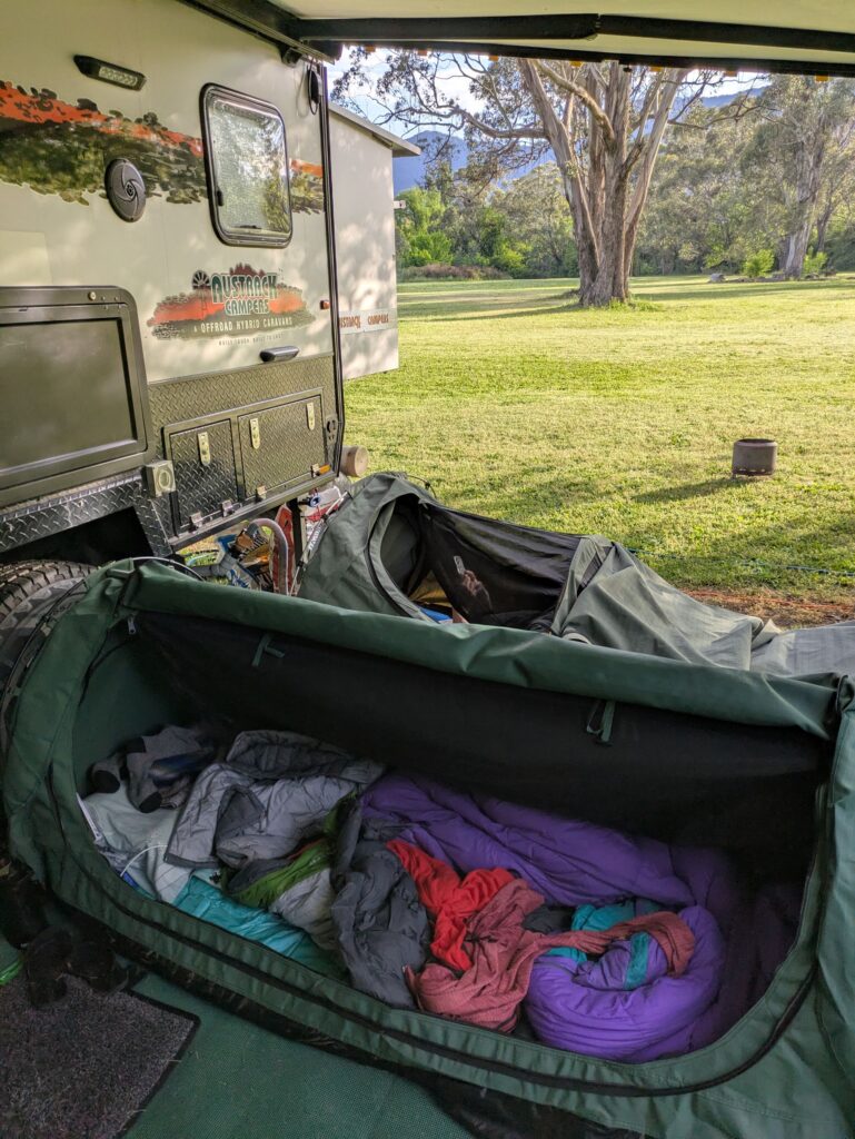 Two swags side by side under an awning of a caravan in a camp ground