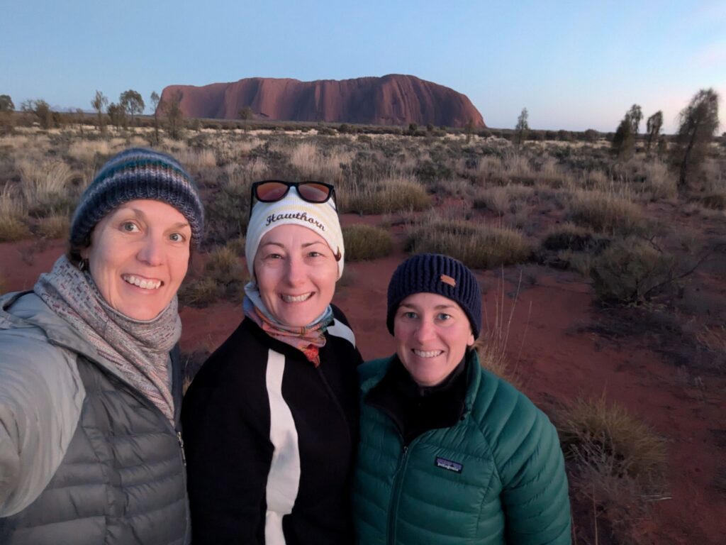 Three friends watching the sun rise at Uluru