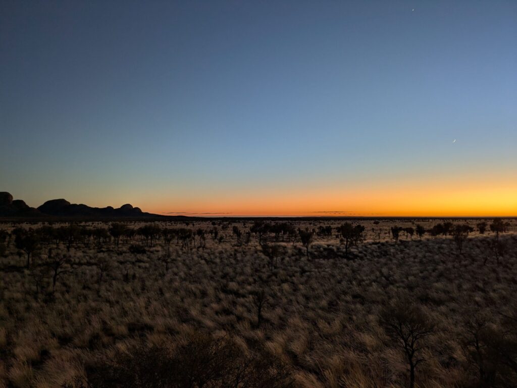 A desert landscape with daylight starting to challenge the night sky