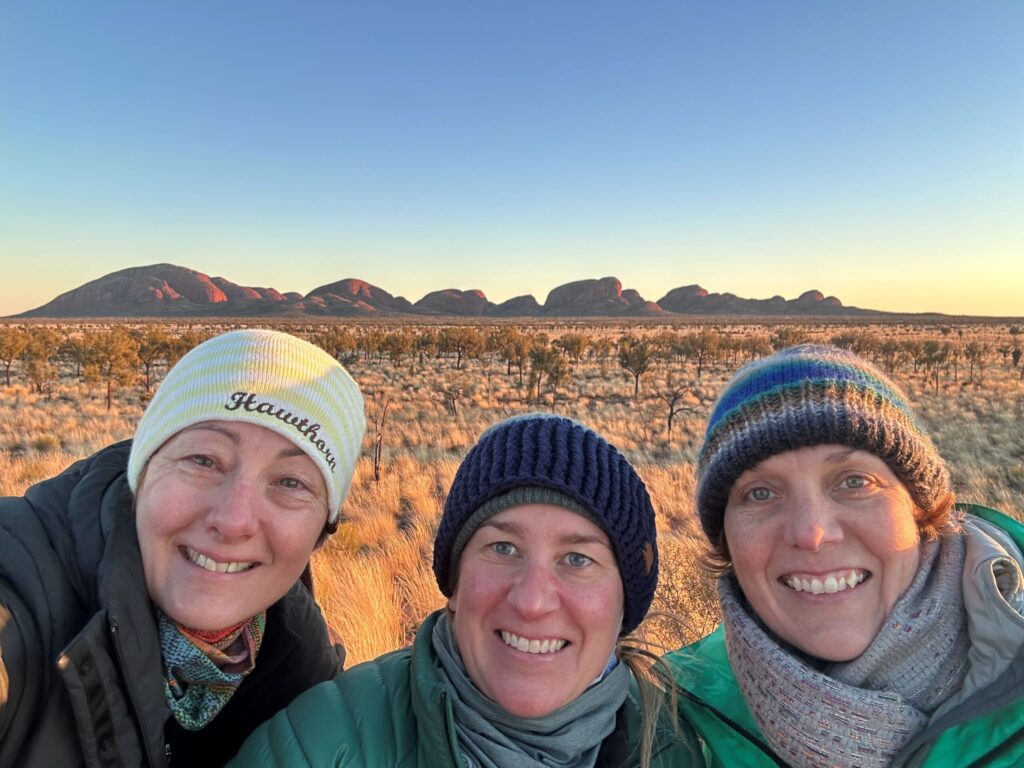 Three friends at sunrise in the desert with a rock formation behind