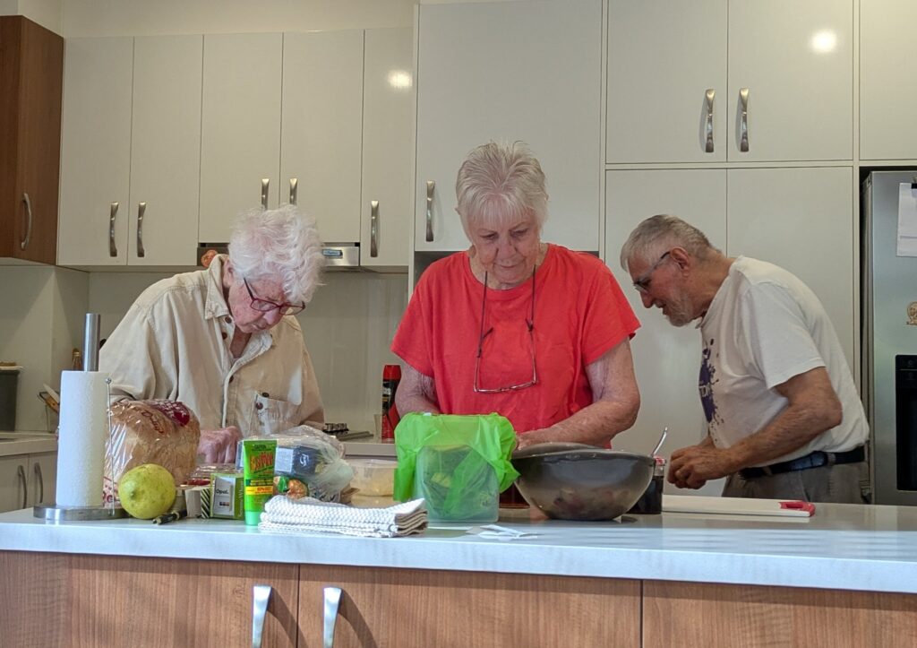 Three older people in the kitchen preparing breakfast