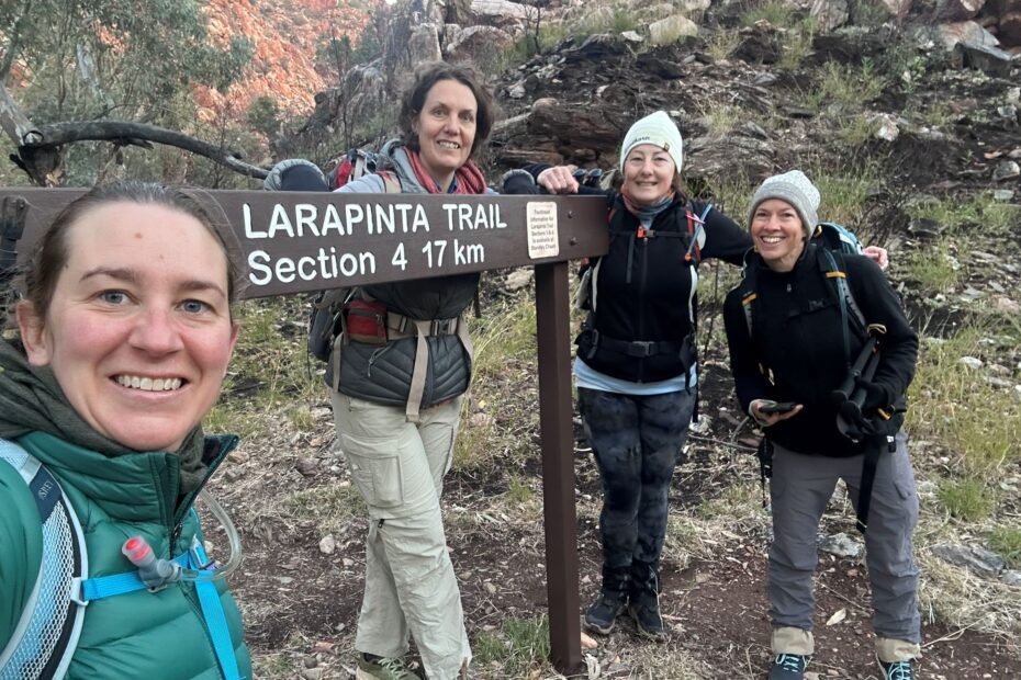 Four women dressed for hiking, standing around a sign indicating the path they are about to take