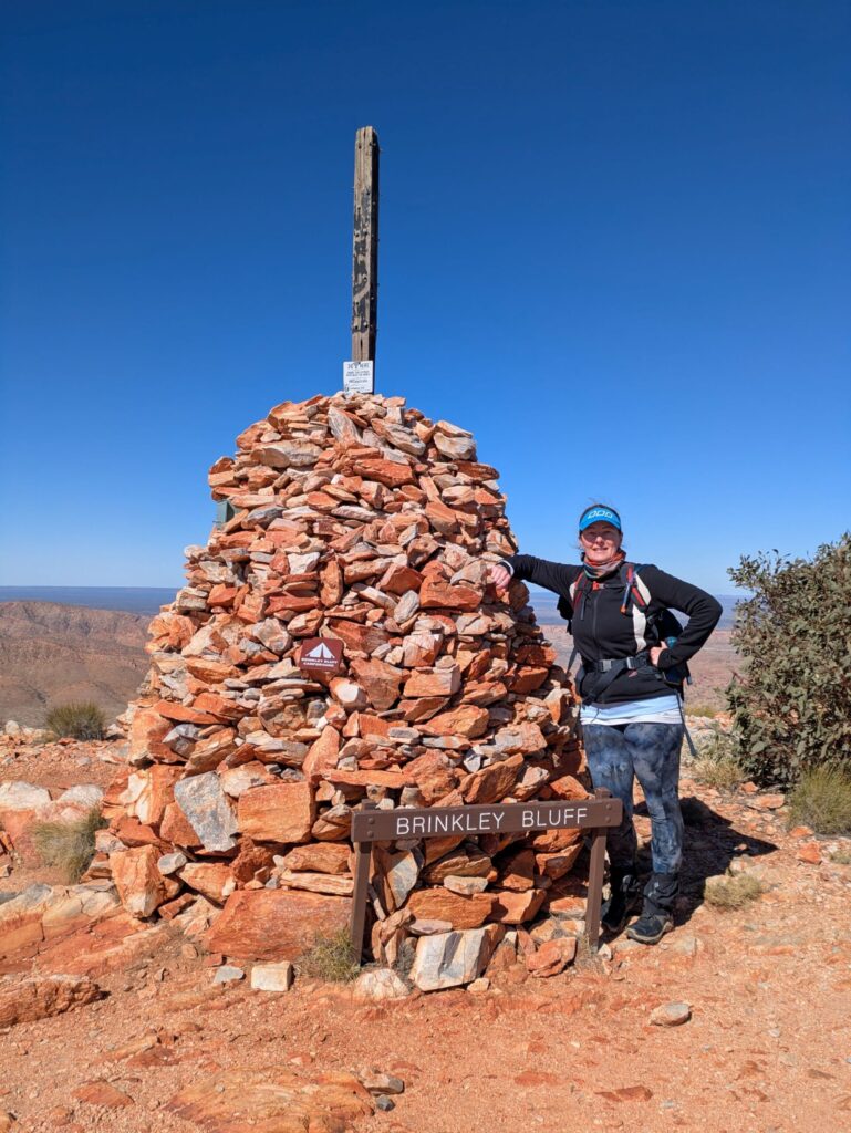 A woman standing next to a tall cairn of rocks marking Brinkley Bluff