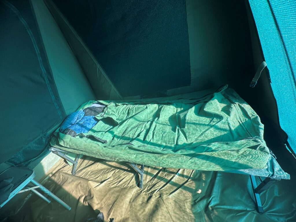 Inside a tent, a picture of the stretcher bed with a swag on it