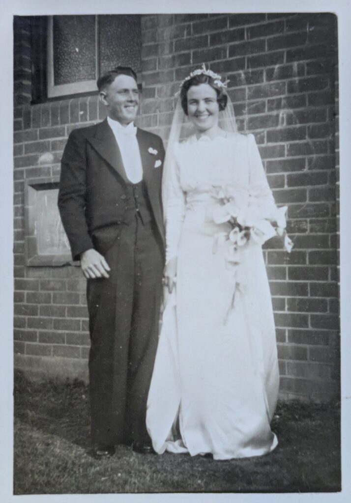 A black & white photo from 1941 of a couple on their wedding day, very happy and smiley