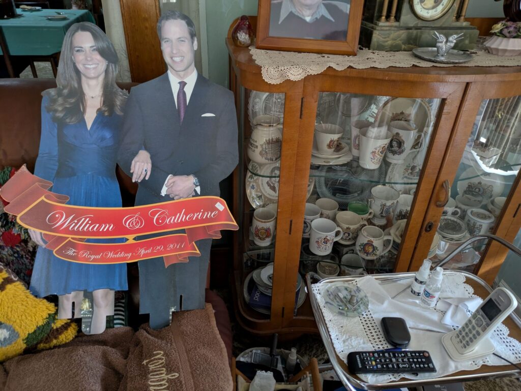 A cardboard cutout of Prince WIlliam and Princess Kate and a side board full of Royal family memorabilia 