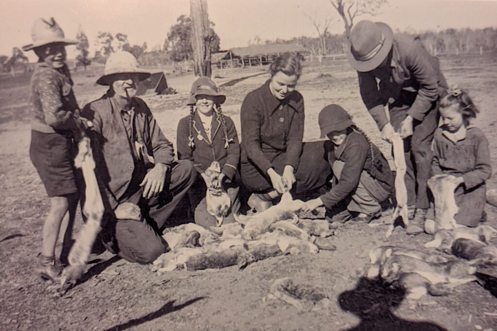 A black and white photo of a family on a dry farm skinning rabbits