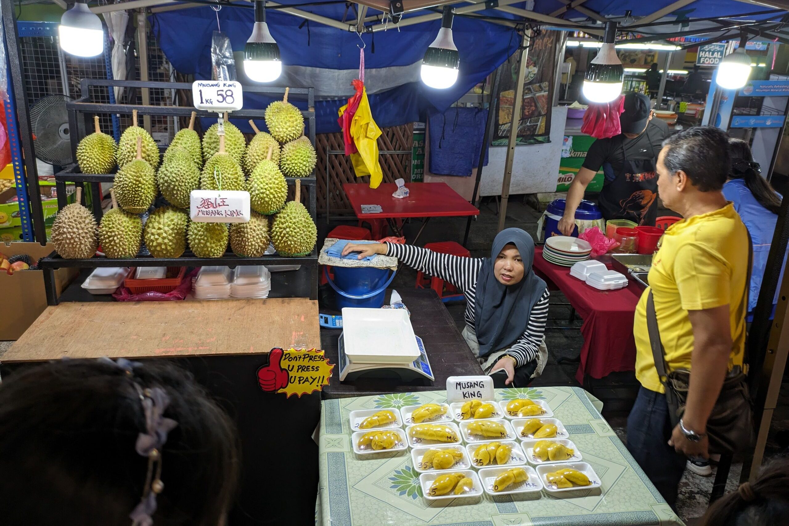 A market stall at street night markets in Malaysia where a woman is selling durians