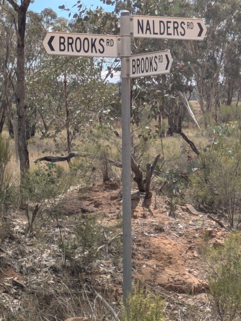 A road sign in outback Australia pointing 3 ways - two to Brooks Road and one to Nalders Road