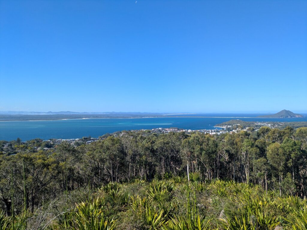 A view from a lookout, looking over a river with a town in the foreground and mountains in the distance