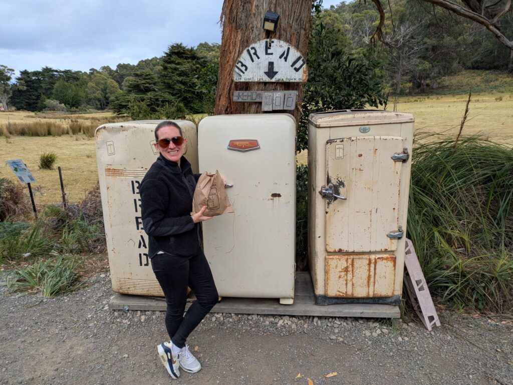 A woman showing off her fresh bread sourced from an old refrigerator on the side of the road