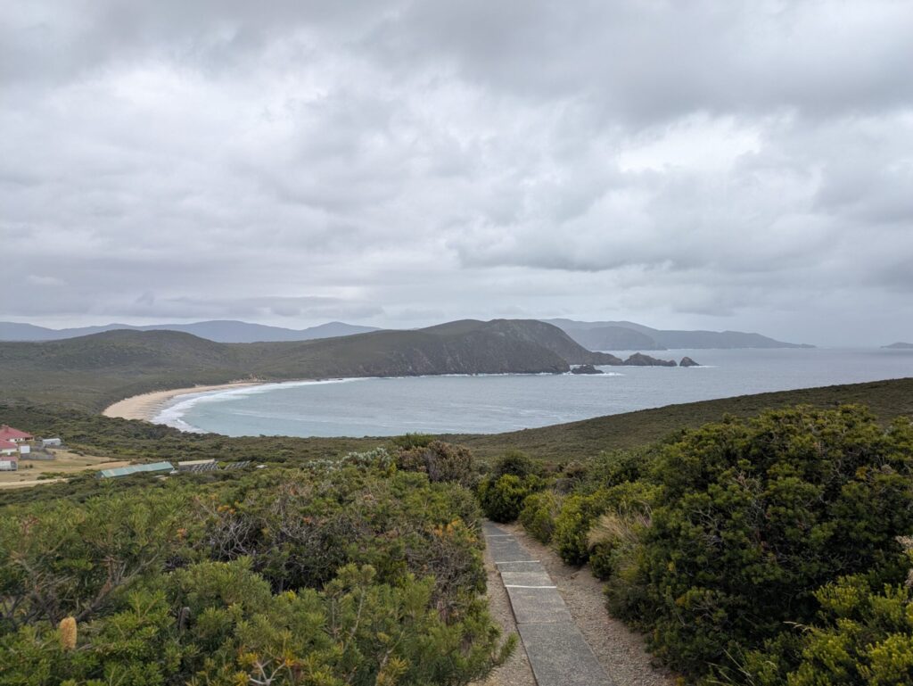 A view from a lighthouse back over the Lighthouse Keeper's house, a large bay and mountains in the distance