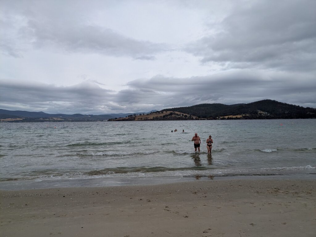 A group of friends swimming in very cold ocean water on a bleak day