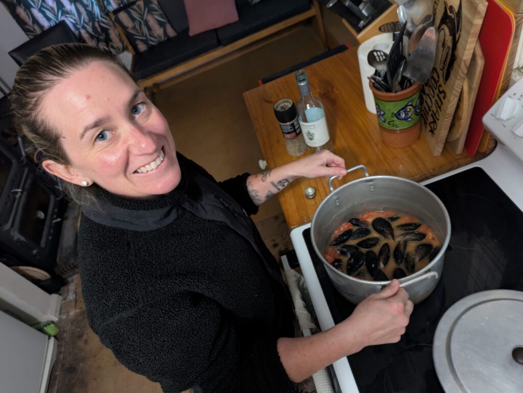 From above, a woman holding a large pot of mussels on the stove
