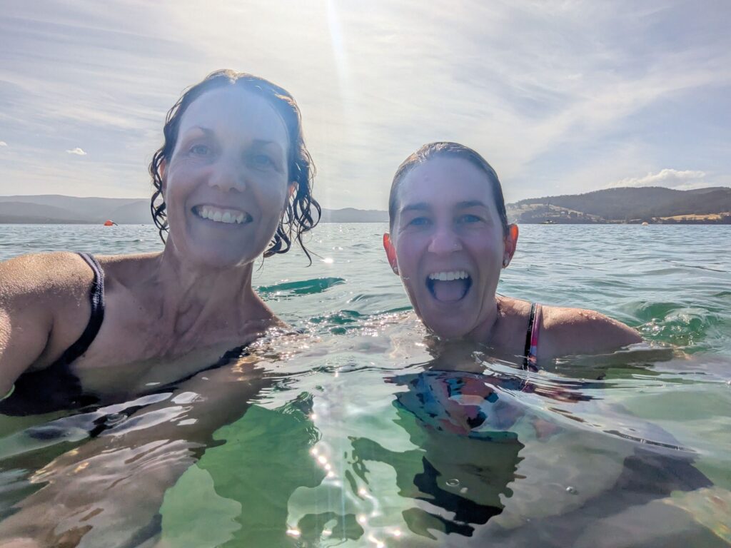 A selfie of two women swimming in the ocean on a sunny day