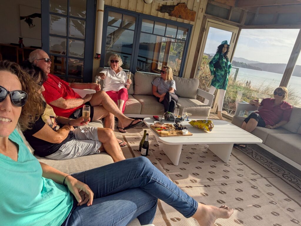 A group of friends sitting on comfortable chairs, enjoying a cheese plate and wine while watching the sunset over the ocean