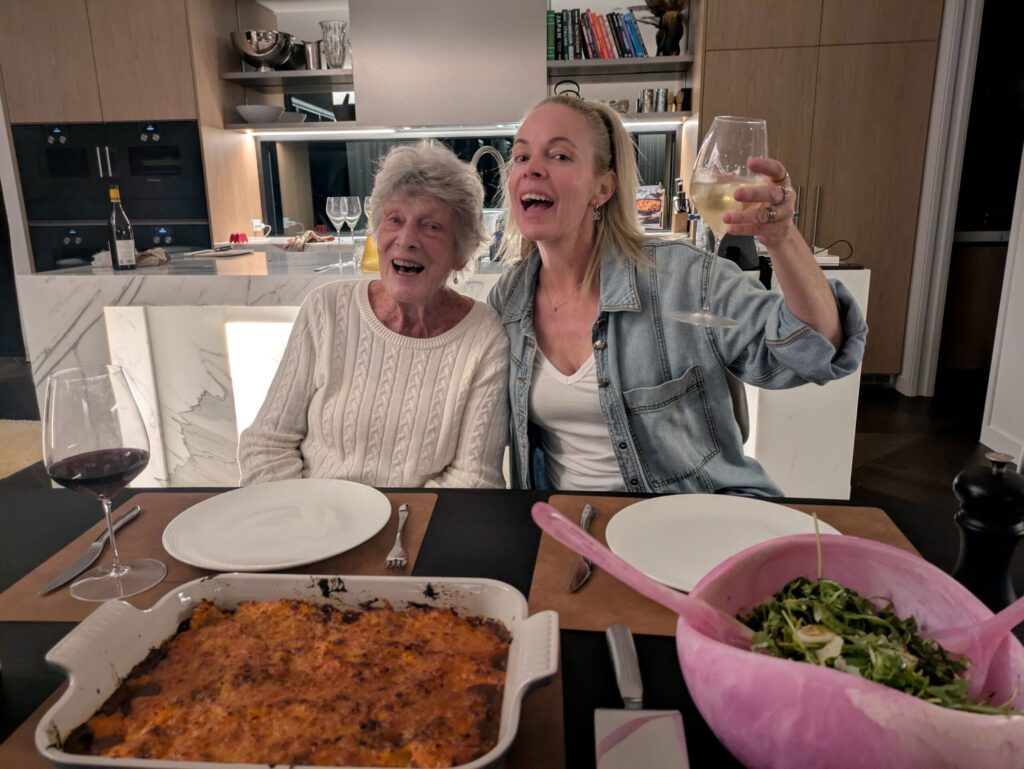 An older woman and her niece sitting at the dining table, singing together
