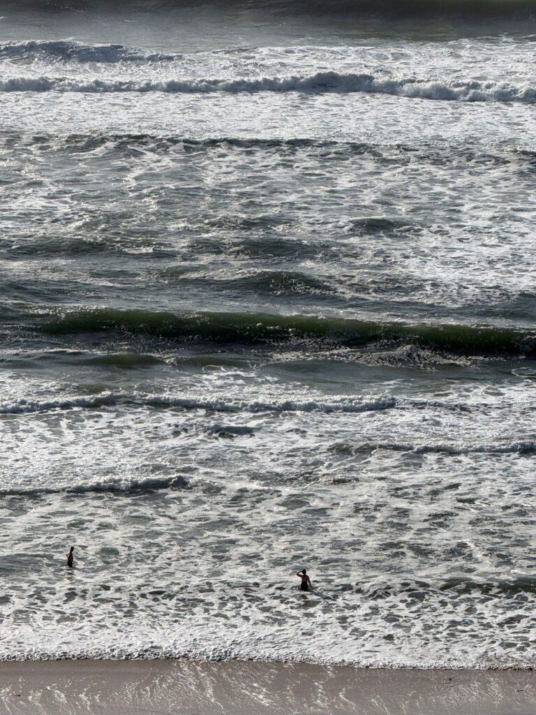 A view from high up of a woman swimming in rough surf conditions