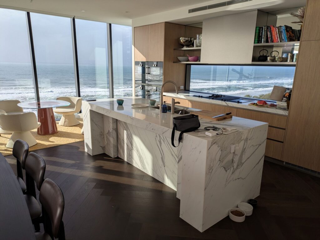 Standing in a kitchen, looking out through the floor to ceiling windows to the ocean