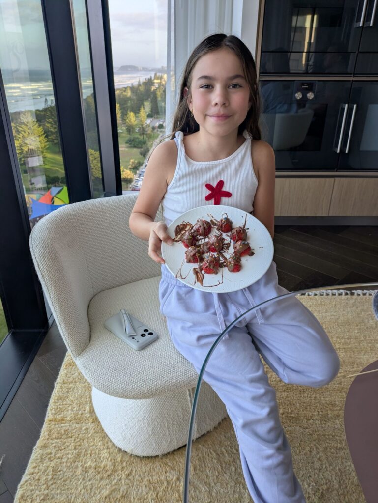 A young girl proudly presenting the strawberries dipped in chocolate she has just made