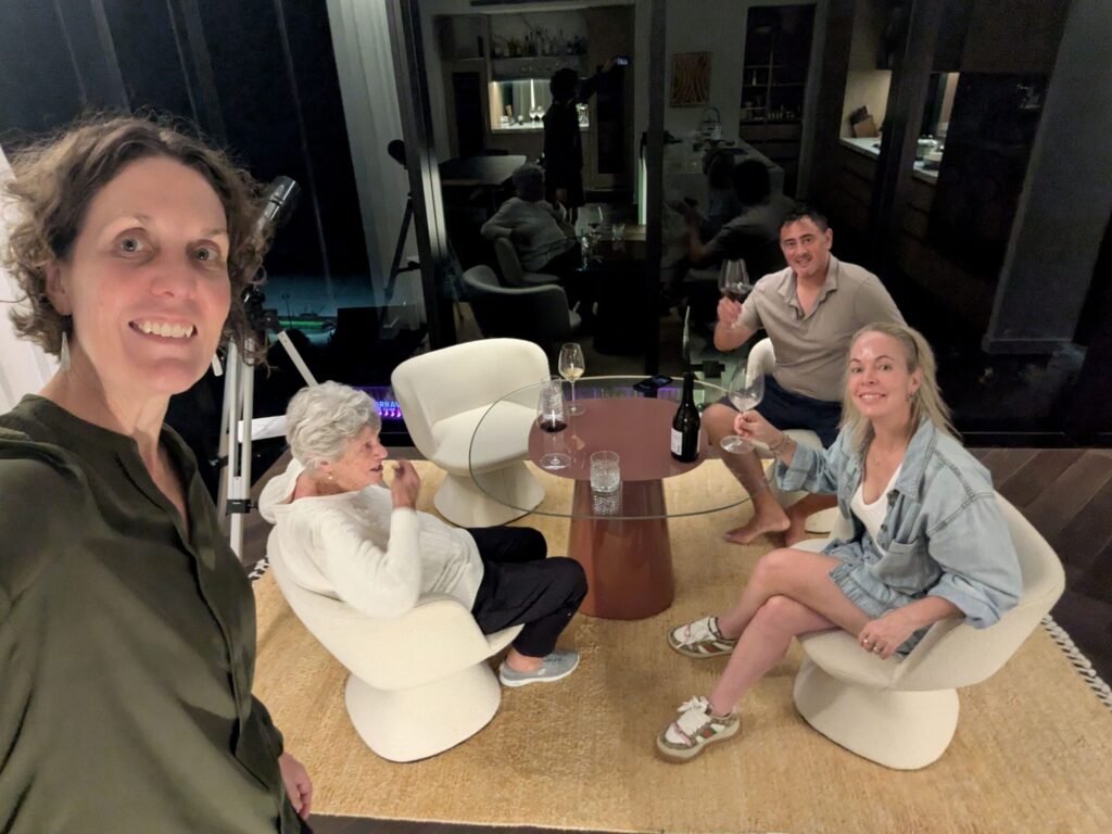 Four family members enjoying a glass of wine around a table and smiling and laughing