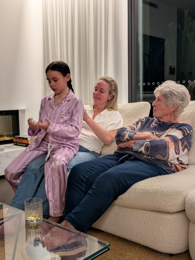 A girl sitting on her mother's lap so her mother can do her hair