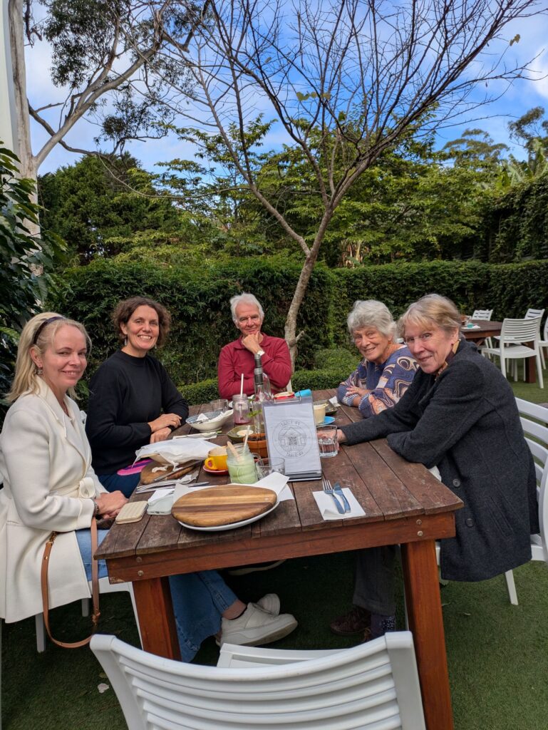 5 friends sitting around a table in a cafe enjoying lunch